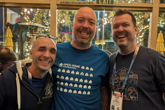 Three men smiling, the middle one is wearing an Open Home Foundation T-shirt.